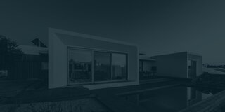 Contemporary single-story house with a cubic design and glass windows, next to a private pool on a wooden deck